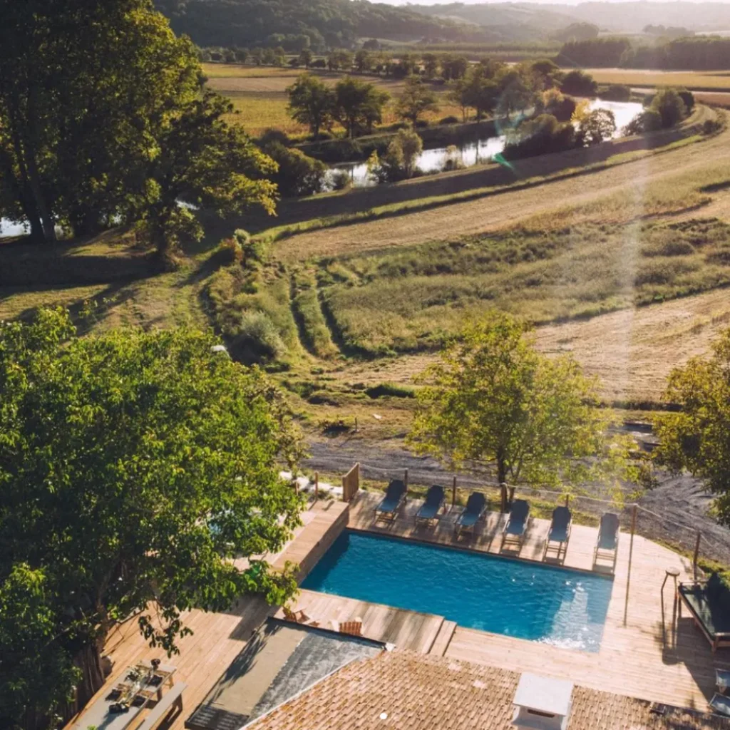 Vue aérienne sur la terrasse avec la piscine et un fleuve au fond du jardin