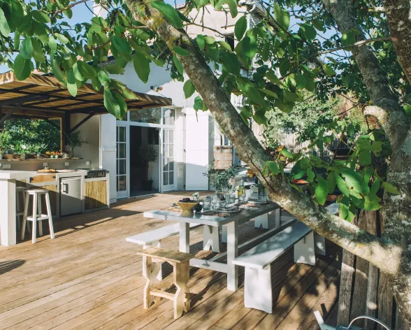 Terrasse en bois avec une table et une cuisine extérieure