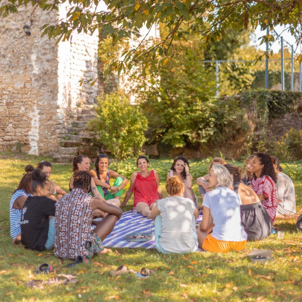Femmes asseyent sur l'herbe en rond entrain de parler lors d'un séjour de danse