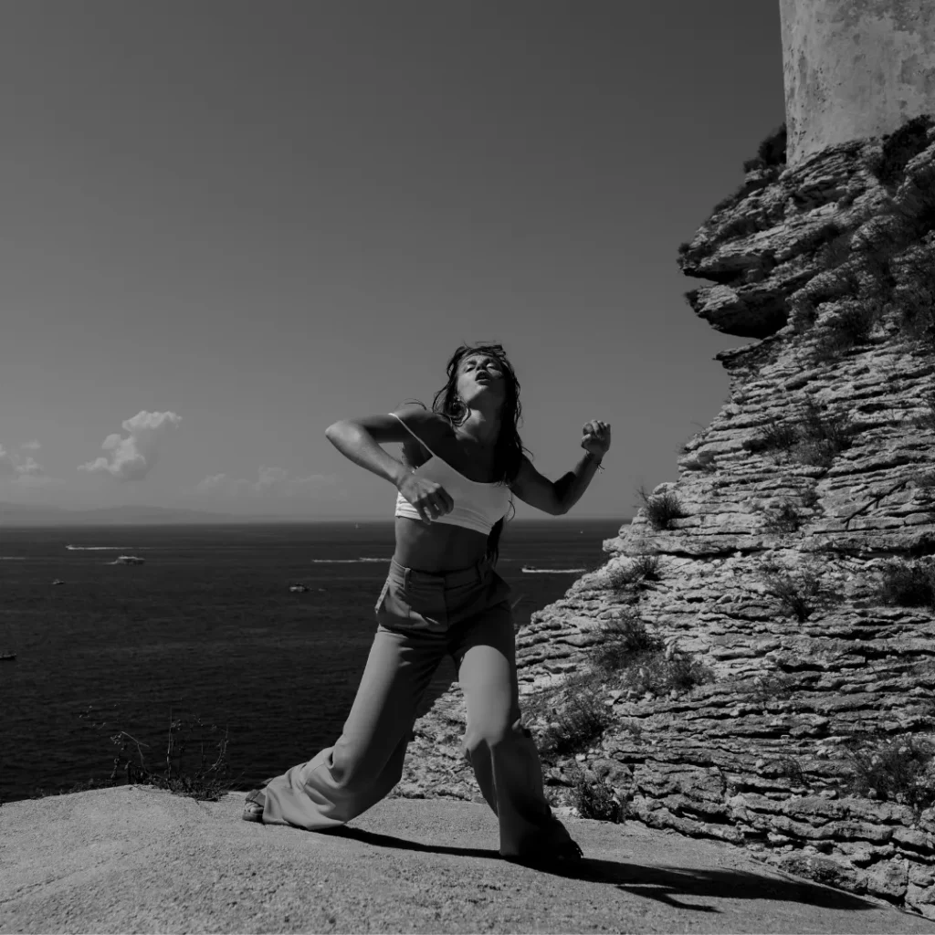 Femme dansant à côté d'un rocher face à la mer