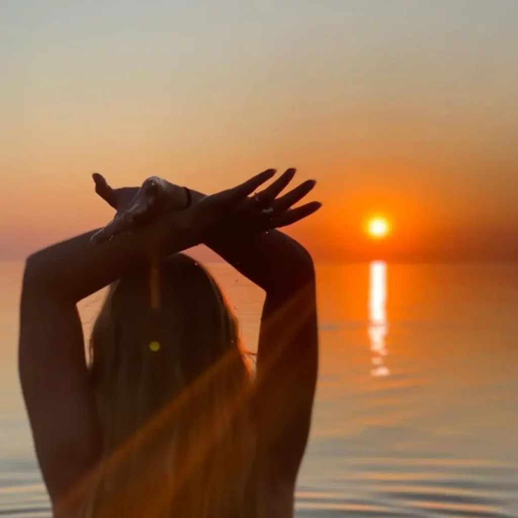 Femme regardant un coucher de soleil face à la mer