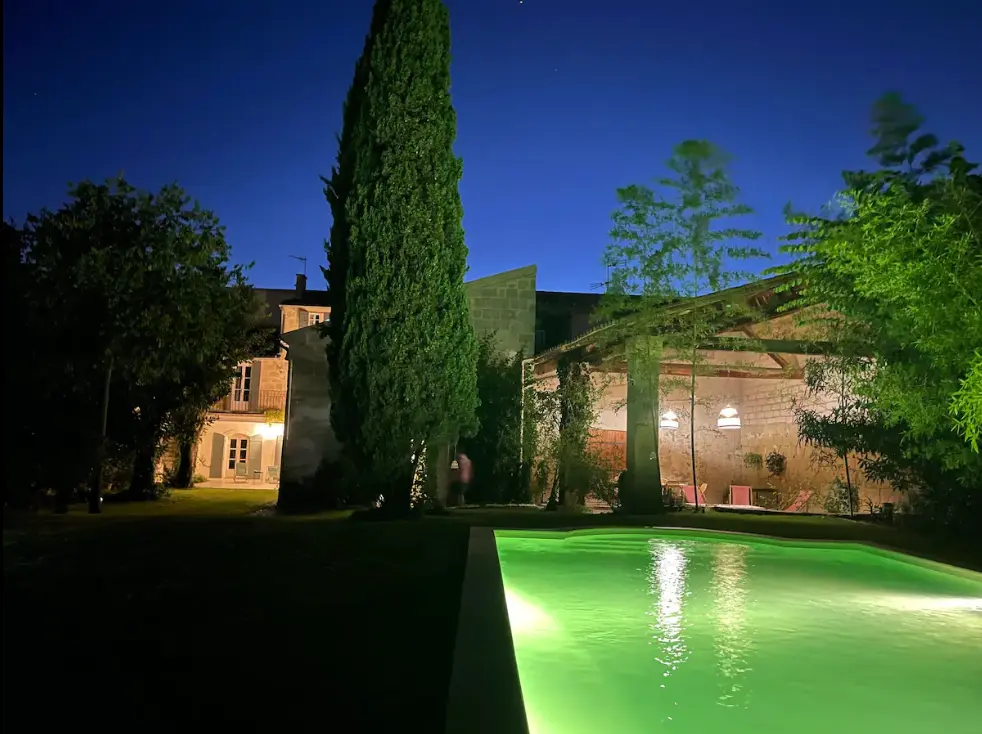 Jardin avec grande piscine, maison en pierre en fond de jardin